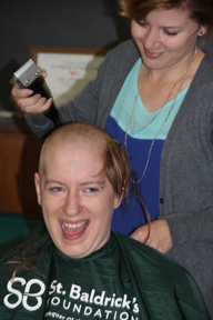 WSLH Purchasing Office Operations Associate Kathleen Cleary smiles while losing her locks. Kathleen said shaving her head to raise money for childhood cancer research was an easy thing to do. "It's just hair," she explained.