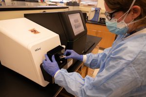 WSLH Microbiologist Tonya Danz loads the flowcell onto the instrument where the SARS-CoV-2 genome is sequenced.