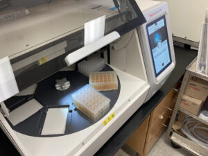 wastewater samples in a 24-well tray are loaded into a scientific instrument for processing